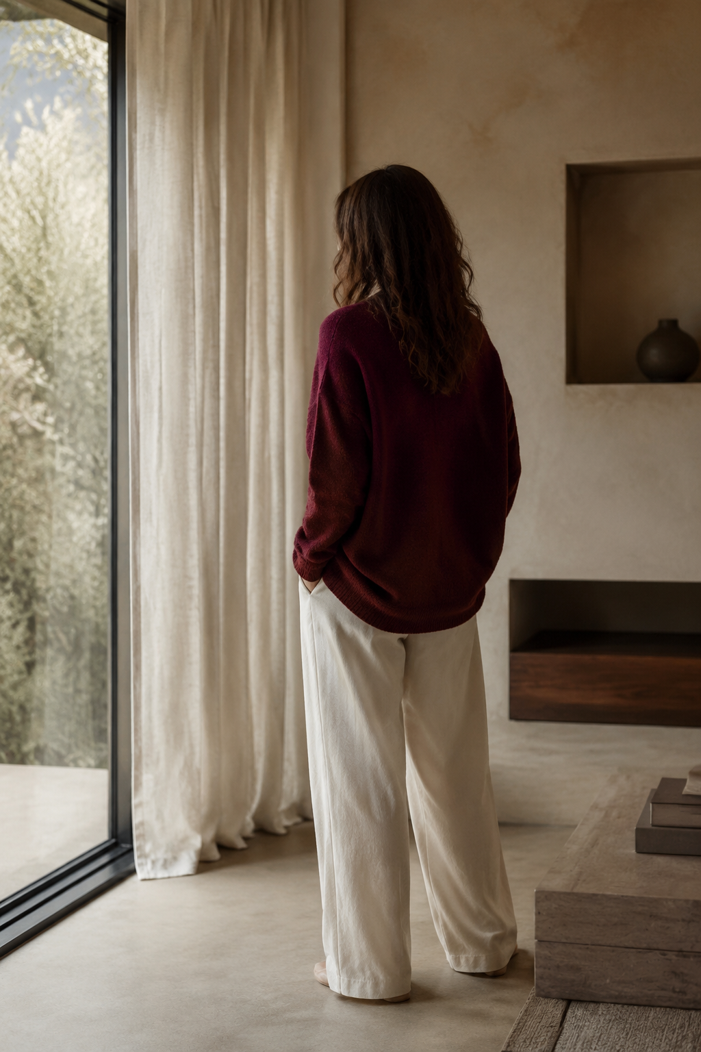 A woman standing quietly by a sunlit window
